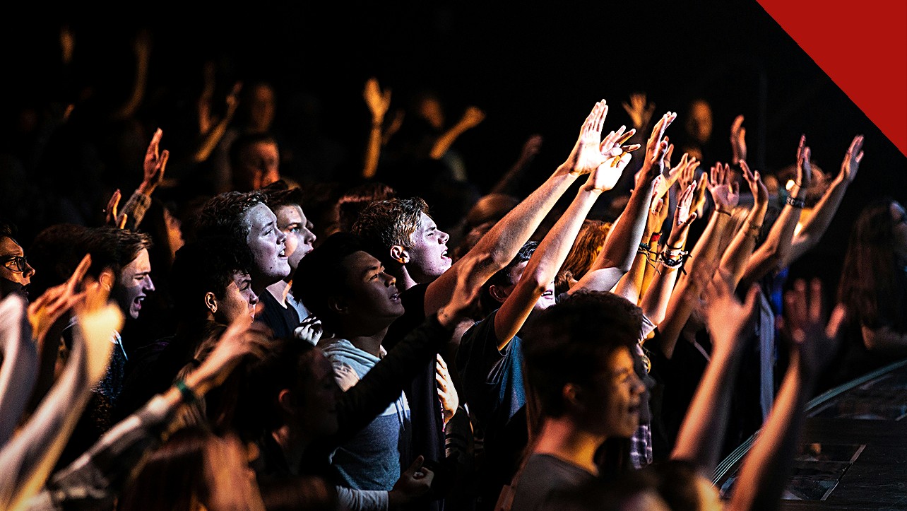jovens adultos frequentam cultos mais que os pais, e a imagem mostra jovens em um culto nos Estados Unidos durante um momento de adoração