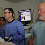 mulher morre após colonoscopia em clínica de SC, e a imagem mostra uma equipe médica acompanhando um monitor durante um procedimento de colonoscopia em foto de arquivo