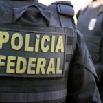PF faz operação contra fraude de 10 bilhões no Maranhão no Seguro Defeso, e a imagem mostra um agente da Polícia Federal de costas com o colete da corporação durante operação
