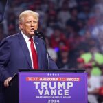 Trump reage à carta de Flávio: Donald Trump discursando em púlpito durante comício no Arizona, nos Estados Unidos