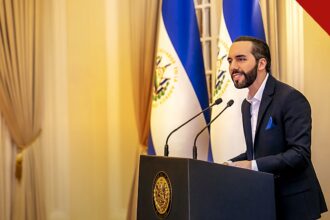 Bukele parabeniza Lula pela vitória: Nayib Bukele em pronunciamento oficial, de terno, diante das bandeiras de El Salvador