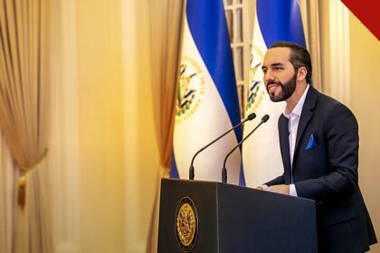 Bukele parabeniza Lula pela vitória: Nayib Bukele em pronunciamento oficial, de terno, diante das bandeiras de El Salvador