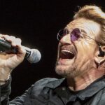 Bono ataca cristãos e judeus: o cantor do U2 canta em show em Indianápolis, nos Estados Unidos, segurando um microfone e usando óculos escuros