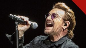Bono ataca cristãos e judeus: o cantor do U2 canta em show em Indianápolis, nos Estados Unidos, segurando um microfone e usando óculos escuros