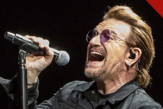 Bono ataca cristãos e judeus: o cantor do U2 canta em show em Indianápolis, nos Estados Unidos, segurando um microfone e usando óculos escuros