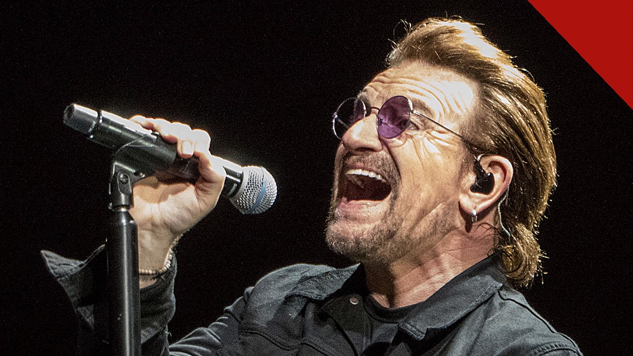 Bono ataca cristãos e judeus: o cantor do U2 canta em show em Indianápolis, nos Estados Unidos, segurando um microfone e usando óculos escuros