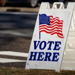 bispos dos Estados Unidos pedem voto a partir da fé, e a imagem mostra uma placa de local de votação nos Estados Unidos com a bandeira americana, às vésperas das eleições de meio de mandato