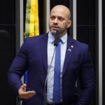 Moraes arquiva inquérito contra Daniel Silveira, e a imagem mostra o ex-deputado Daniel Silveira discursando de terno azul na tribuna da Câmara dos Deputados