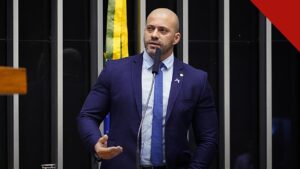 Moraes arquiva inquérito contra Daniel Silveira, e a imagem mostra o ex-deputado Daniel Silveira discursando de terno azul na tribuna da Câmara dos Deputados