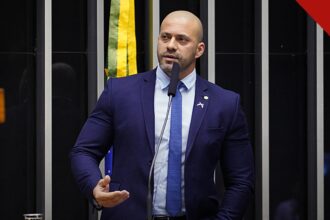 Moraes arquiva inquérito contra Daniel Silveira, e a imagem mostra o ex-deputado Daniel Silveira discursando de terno azul na tribuna da Câmara dos Deputados