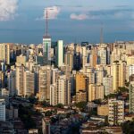 São Paulo registra queda de 33% nos latrocínios, e a imagem mostra uma vista aérea panorâmica da cidade de São Paulo, com prédios e torres de transmissão ao entardecer