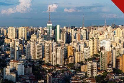 São Paulo registra queda de 33% nos latrocínios, e a imagem mostra uma vista aérea panorâmica da cidade de São Paulo, com prédios e torres de transmissão ao entardecer