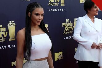 Kim Kardashian faz cirurgia após diagnóstico de esofagite, e a imagem mostra Kim Kardashian de vestido branco ao lado da mãe, Kris Jenner, no tapete vermelho de uma premiação da MTV