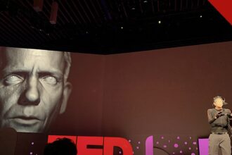 polícia desarticula esquema com deepfake de famosos, e a imagem mostra uma demonstração de deepfake em telão no TED 2019, com um rosto digital projetado ao lado do apresentador