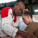 Mingau fica de pé na fisioterapia em imagem ilustrativa de um paciente em exercício de caminhada assistido por um fisioterapeuta, em referência à recuperação do baixista do Ultraje a Rigor