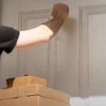 compras internacionais terão novo imposto em 2027, e a imagem mostra um entregador batendo à porta de uma residência com caixas de encomendas ao lado