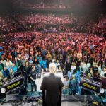 Franklin Graham vê sinais de avivamento: o evangelista de costas no púlpito diante de mais de 10 mil pessoas na arena de Manchester, na turnê God Loves You