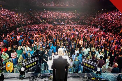 Franklin Graham vê sinais de avivamento: o evangelista de costas no púlpito diante de mais de 10 mil pessoas na arena de Manchester, na turnê God Loves You