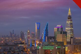 Estados Unidos retiram funcionários da Arábia Saudita, e a imagem mostra o horizonte de Riade, capital da Arábia Saudita, ao entardecer, com torres iluminadas como a Kingdom Tower e a Al Faisaliah, cidade onde fica a embaixada americana