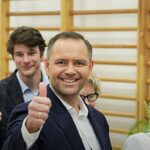 Parlamento da Polônia flexibiliza o aborto: o presidente Karol Nawrocki, de terno escuro, faz sinal de positivo ao lado da esposa em seção eleitoral