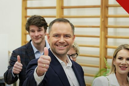 Parlamento da Polônia flexibiliza o aborto: o presidente Karol Nawrocki, de terno escuro, faz sinal de positivo ao lado da esposa em seção eleitoral