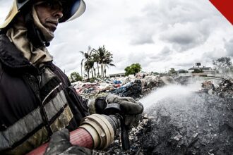 incêndio atinge galpão em Mauá: bombeiro do Corpo de Bombeiros combate chamas em galpão industrial com jato de água