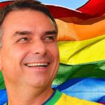 Flávio Bolsonaro busca apoio LGBTQIA+: o candidato do PL sorrindo com a camisa da seleção brasileira diante da bandeira do arco-íris, em montagem do portal a partir da arte da matéria