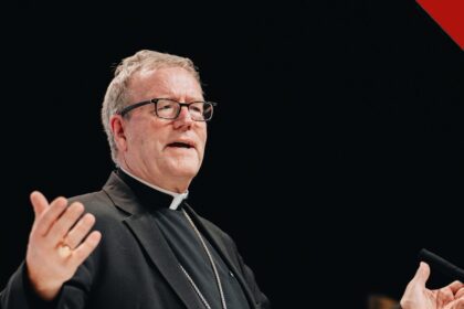 O bispo Barron critica academia alemã: o bispo Robert Barron falando em palestra, de batina preta e cruz peitoral