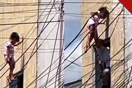 Criança de 5 anos pendurada na fiação elétrica e sendo resgatada por policial em Delmiro Gouveia, Alagoas
