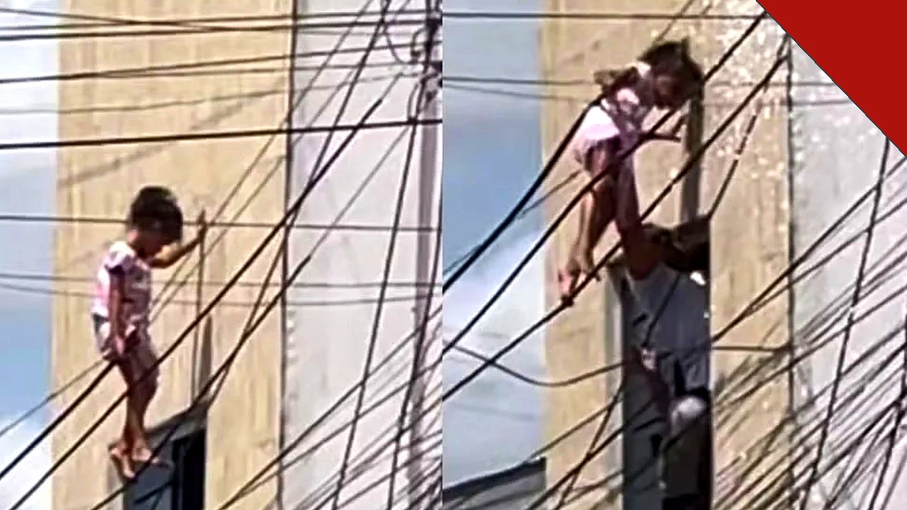 Criança de 5 anos pendurada na fiação elétrica e sendo resgatada por policial em Delmiro Gouveia, Alagoas