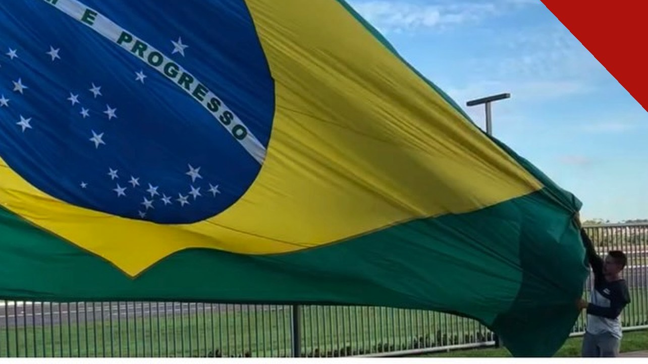 Brasil decide hoje: bandeira gigante do Brasil segurada por um homem em dia de votação do segundo turno