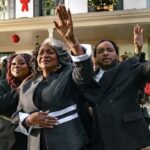Cena do filme de Natal de Tyler Perry, The Gospel of Christmas, com fiéis de mãos levantadas diante de casa decorada para o Natal