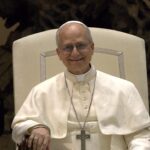 Papa Leão XIV fala com Zelensky: pontífice de vestes brancas e cruz peitoral sorri sentado durante evento no Vaticano
