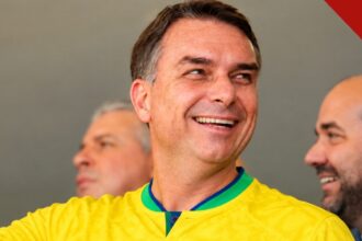 Flávio Bolsonaro busca apoio LGBTQIA+: o candidato do PL sorrindo com a camisa da seleção brasileira, em foto do acervo usada nas composições do portal