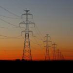 Torres de transmissão de energia ao pôr do sol ilustram a projeção da Aneel para a conta de luz no Nordeste em 2027