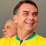 Flávio Bolsonaro sorrindo com a camisa da seleção brasileira; pedido da PF contra Flávio Bolsonaro foi assinado sete minutos após a confirmação da derrota no segundo turno