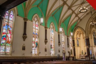 Interior de uma igreja nos Estados Unidos com bancos vazios e vitrais coloridos