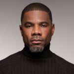 Kirk Franklin em retrato de estúdio com gola preta, olhando para a câmera