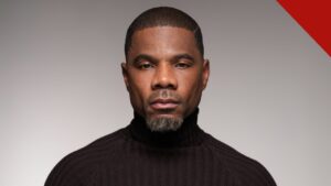 Kirk Franklin em retrato de estúdio com gola preta, olhando para a câmera