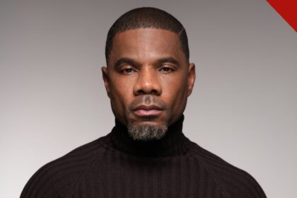 Kirk Franklin em retrato de estúdio com gola preta, olhando para a câmera