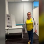 primeira pessoa a votar no segundo turno: Luziene Alves ao lado da cabina de votação na Embaixada do Brasil em Wellington