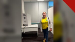 primeira pessoa a votar no segundo turno: Luziene Alves ao lado da cabina de votação na Embaixada do Brasil em Wellington