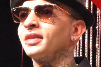 MC Guimê, de chapéu e óculos escuros, com as tatuagens do rosto e do pescoço à mostra, em retrato de 2015