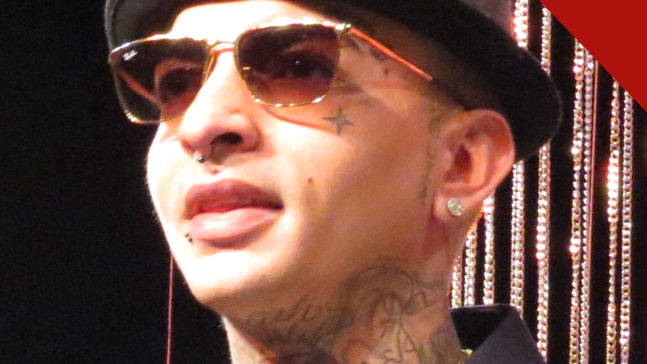 MC Guimê, de chapéu e óculos escuros, com as tatuagens do rosto e do pescoço à mostra, em retrato de 2015