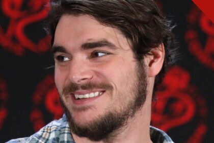 RJ Mitte sorrindo durante evento com fãs, de camisa xadrez