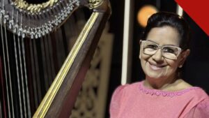 morre Sara Araújo: a cantora gospel pioneira sorrindo ao lado de uma harpa, de vestido rosa