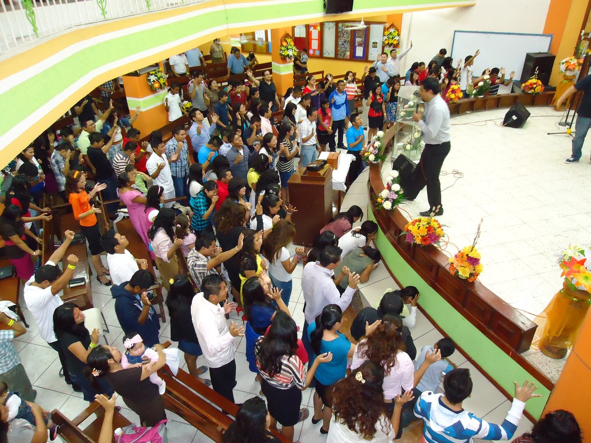 Culto em igreja com fiéis reunidos em momento de oração