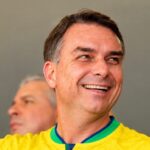 Flávio Bolsonaro fora do Brasil é o relato atribuído a aliados pela CNN Brasil, e a imagem mostra o senador Flávio Bolsonaro sorrindo com a camisa da seleção brasileira