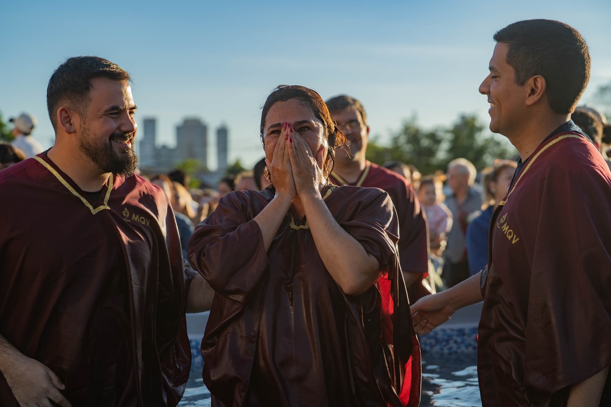 Fiéis reunidos em celebração de batismo nas águas em uma igreja evangélica