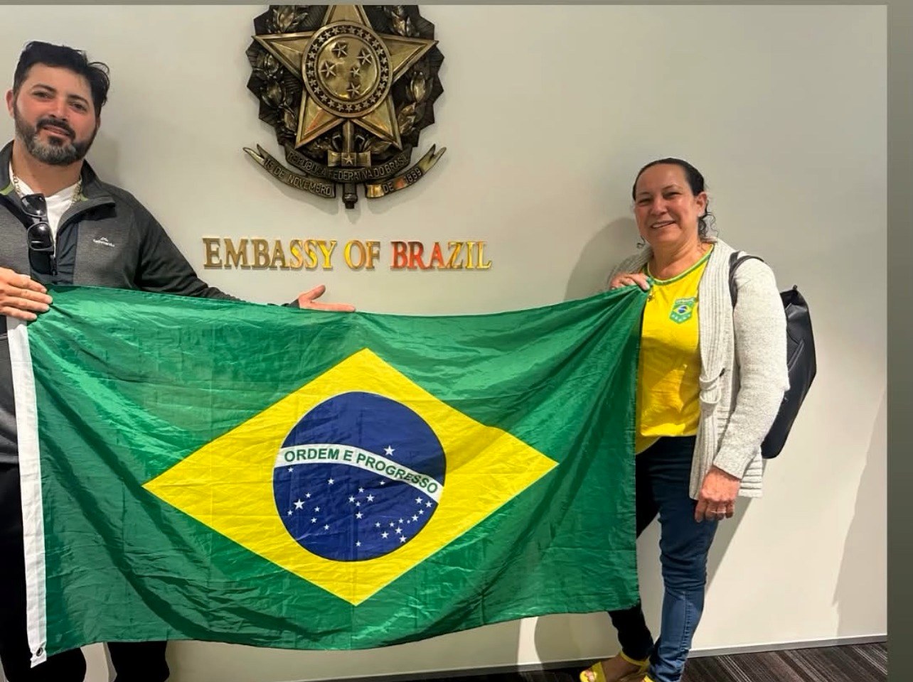 Luziene Alves segurando a bandeira do Brasil na Embaixada do Brasil em Wellington, na Nova Zelândia